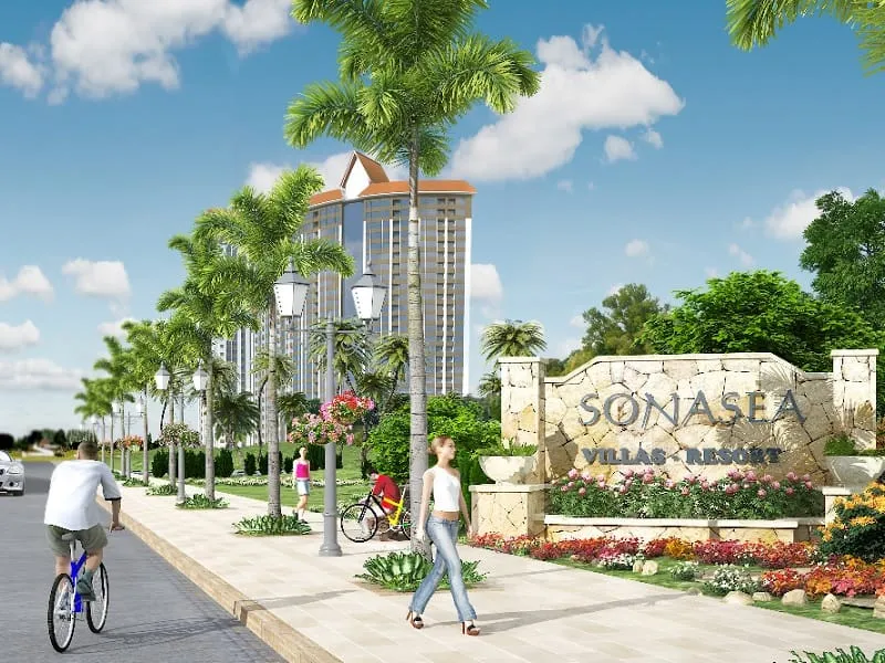 A 3D rendering of a resort entrance with palm trees lining a street, a tall building, and a stone sign reading “SONASEA VILLAS + RESORT”.