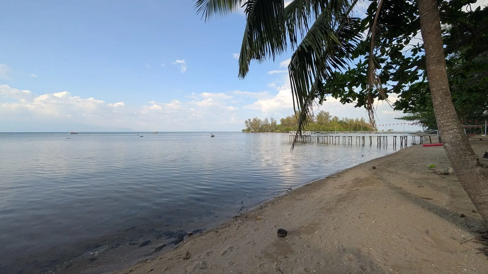 Calm water and a wooden jetty on the coast at Bai Thom, with Hon Mot islet offshore