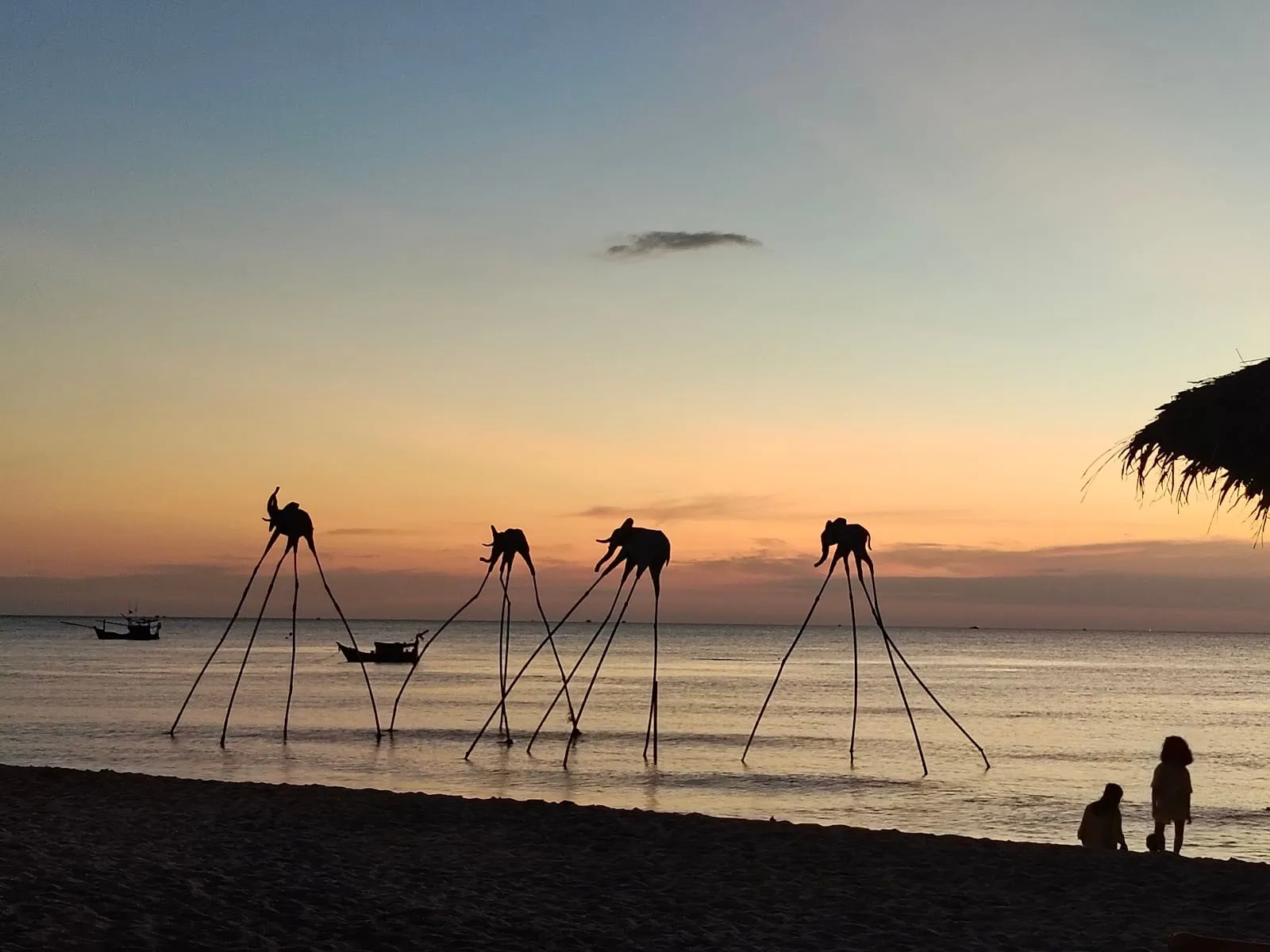 Elephant sculptures on stilts in the sea at Sunset Sanato at dusk