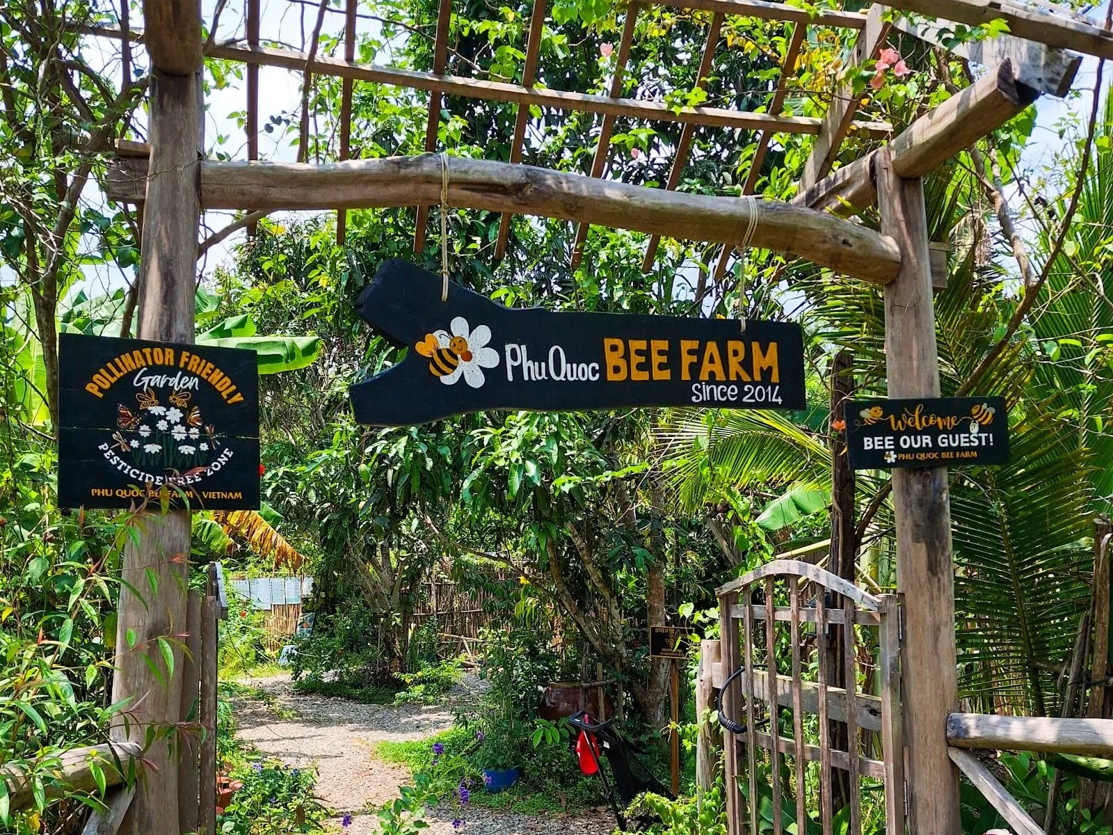 The wooden entrance gate and sign of Phu Quoc Bee Farm among tropical plants