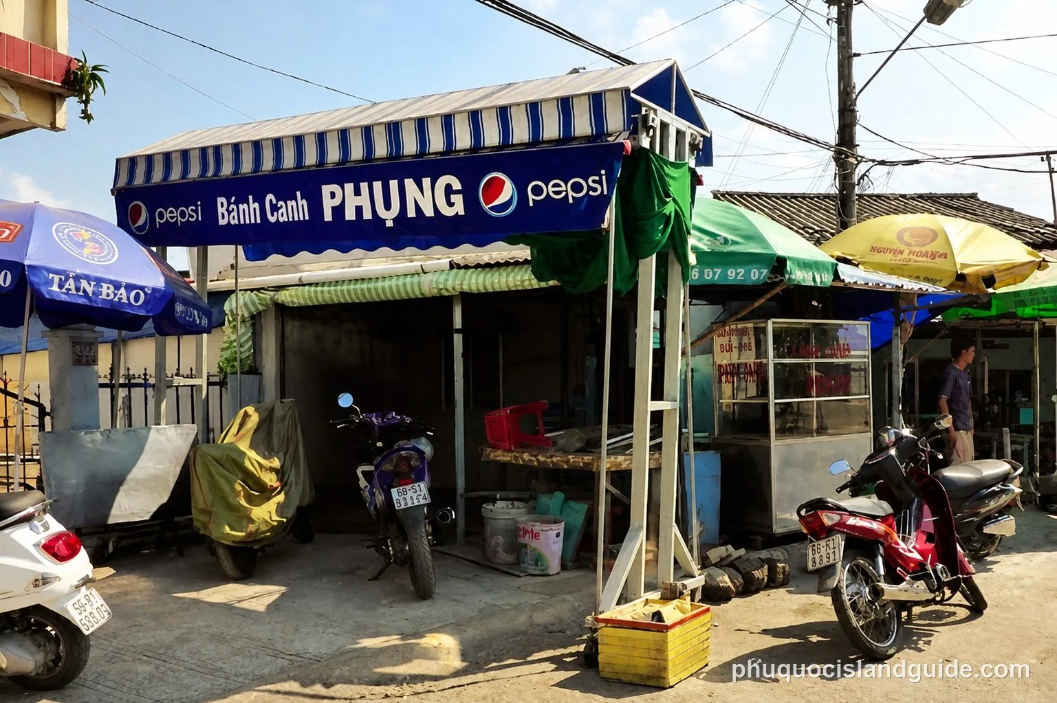 Street food stall with a blue awning selling bánh canh