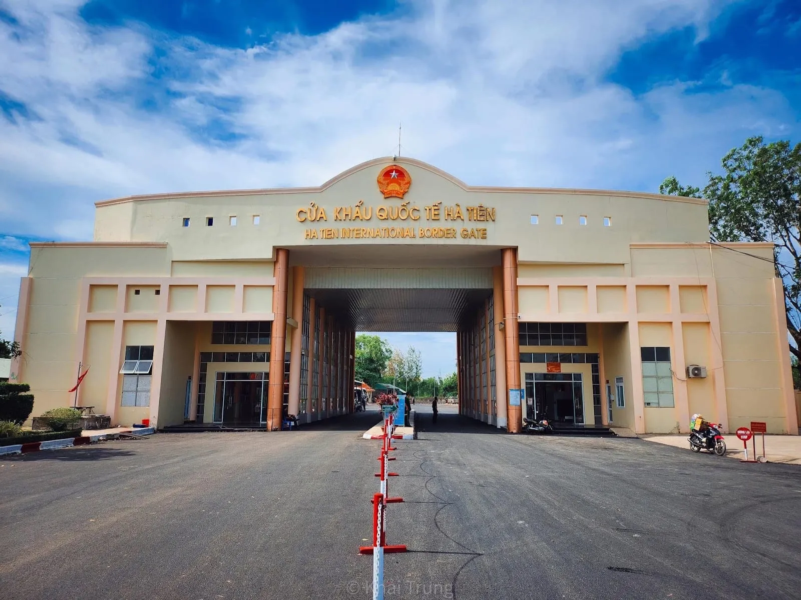 The cream-coloured Ha Tien international border gate building with a road and barrier leading through its central arch