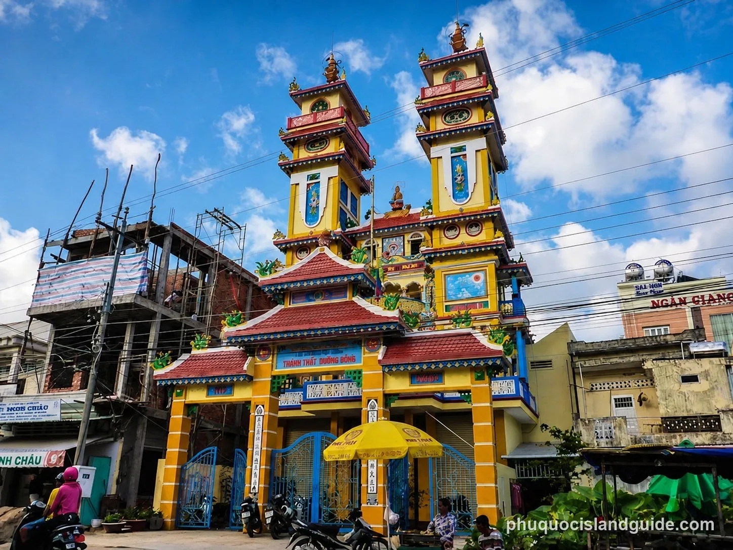 Ornate Cao Dai temple with two towers and a decorative gate