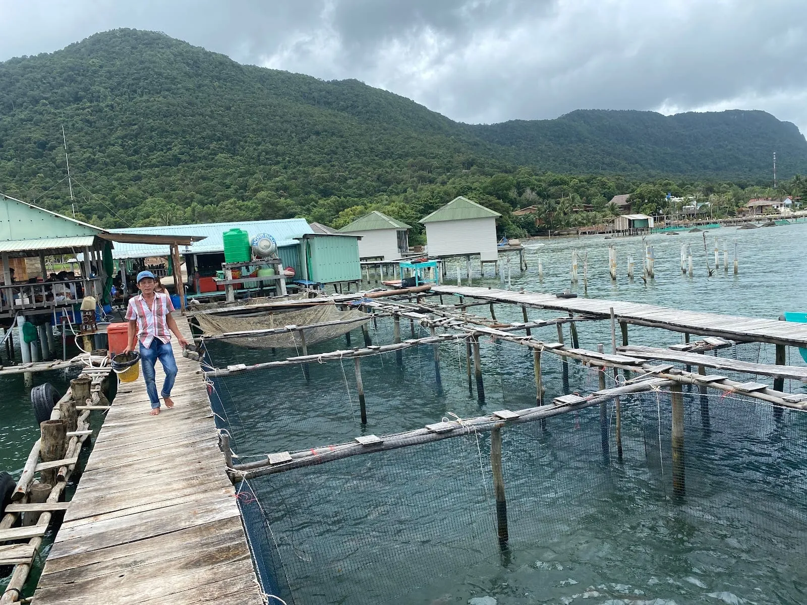 A stilt seafood restaurant over the water at Cay Sao, with the mountains behind