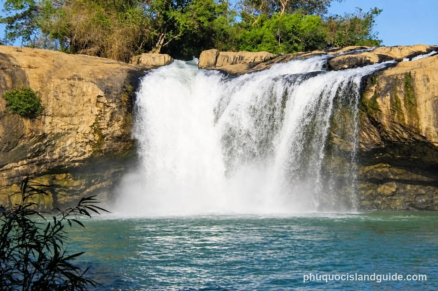 Waterfall pouring over rocky cliffs into a clear pool