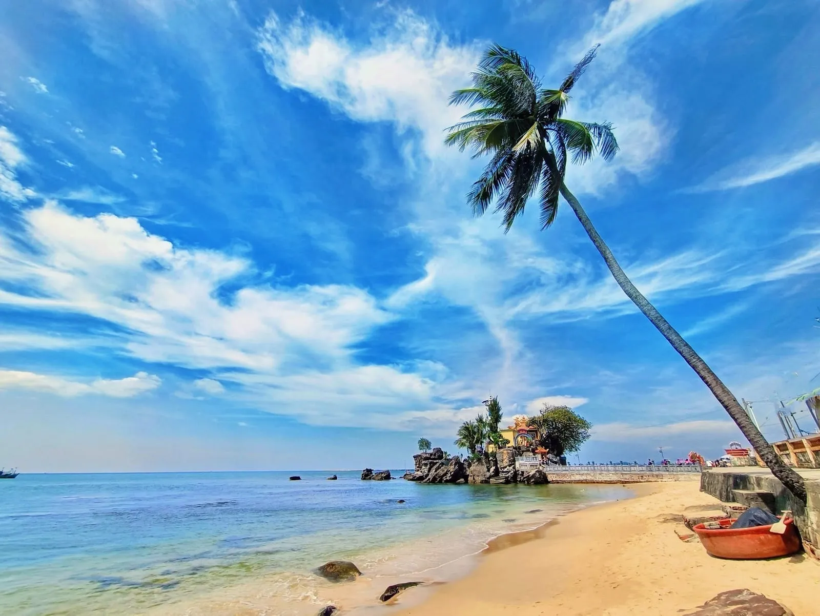 Dinh Cau rock shrine seen from the beach with a leaning palm
