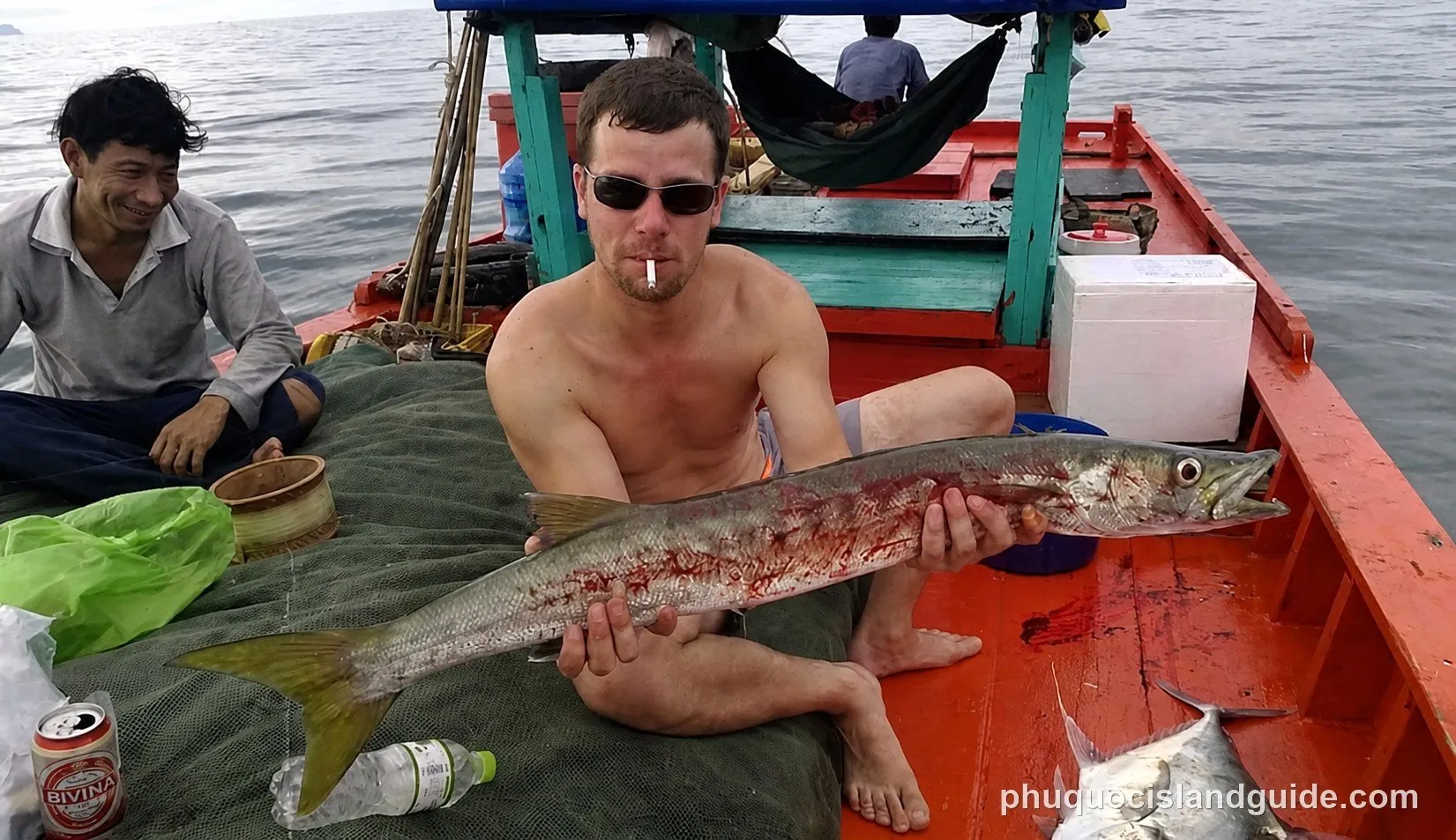 Man on a boat holding a large freshly caught fish