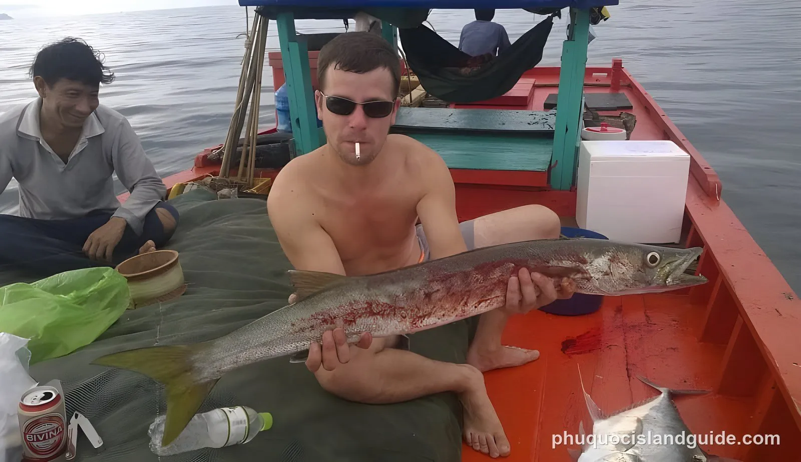 Man on a boat holding a large freshly caught fish