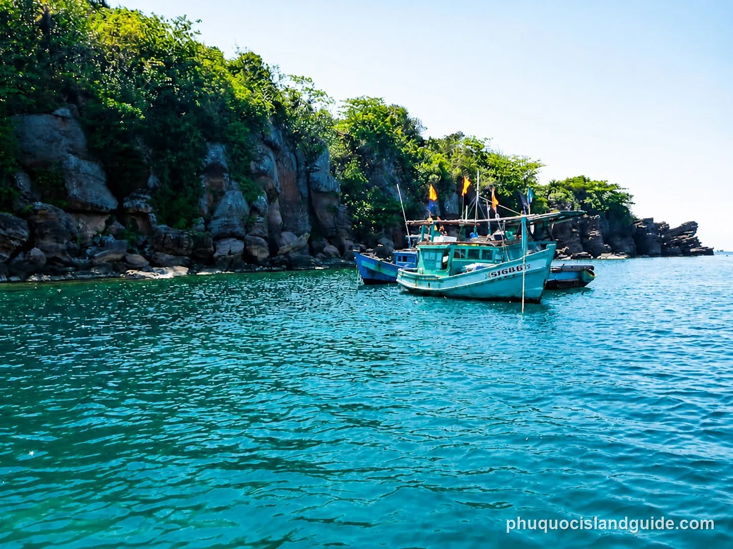 Two fishing boats anchored off a rocky green island