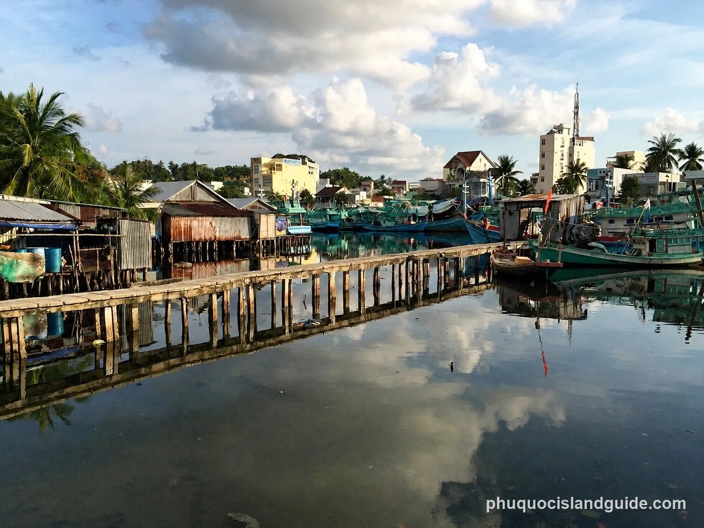 Stilt houses, a wooden pier and fishing boats on the Duong Dong River