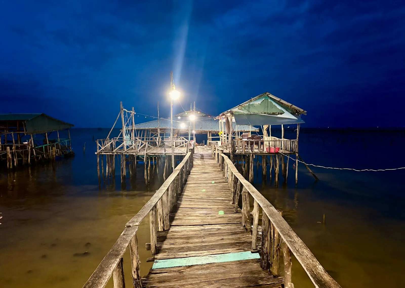 A wooden jetty lit up at night leading to Ngoc Han stilt restaurant in Ham Ninh