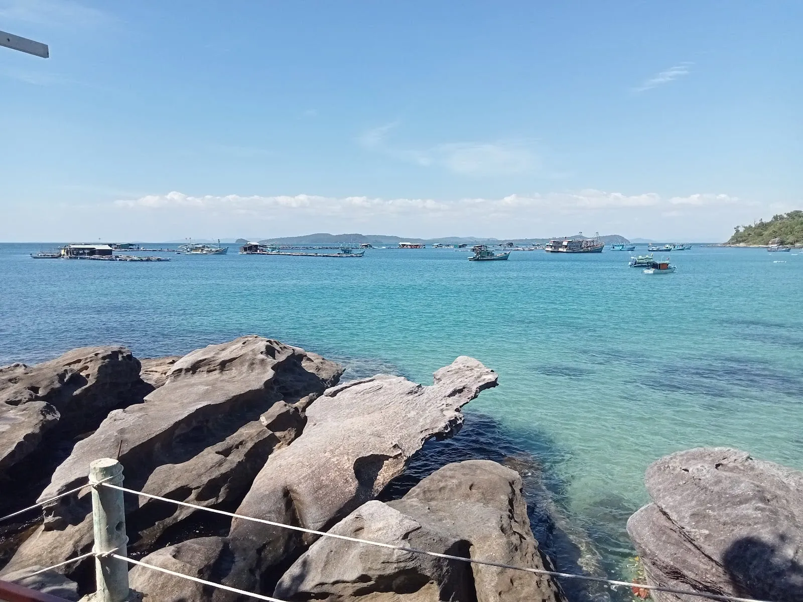 A rocky cove with clear water and fishing boats off the Ganh Dau coast