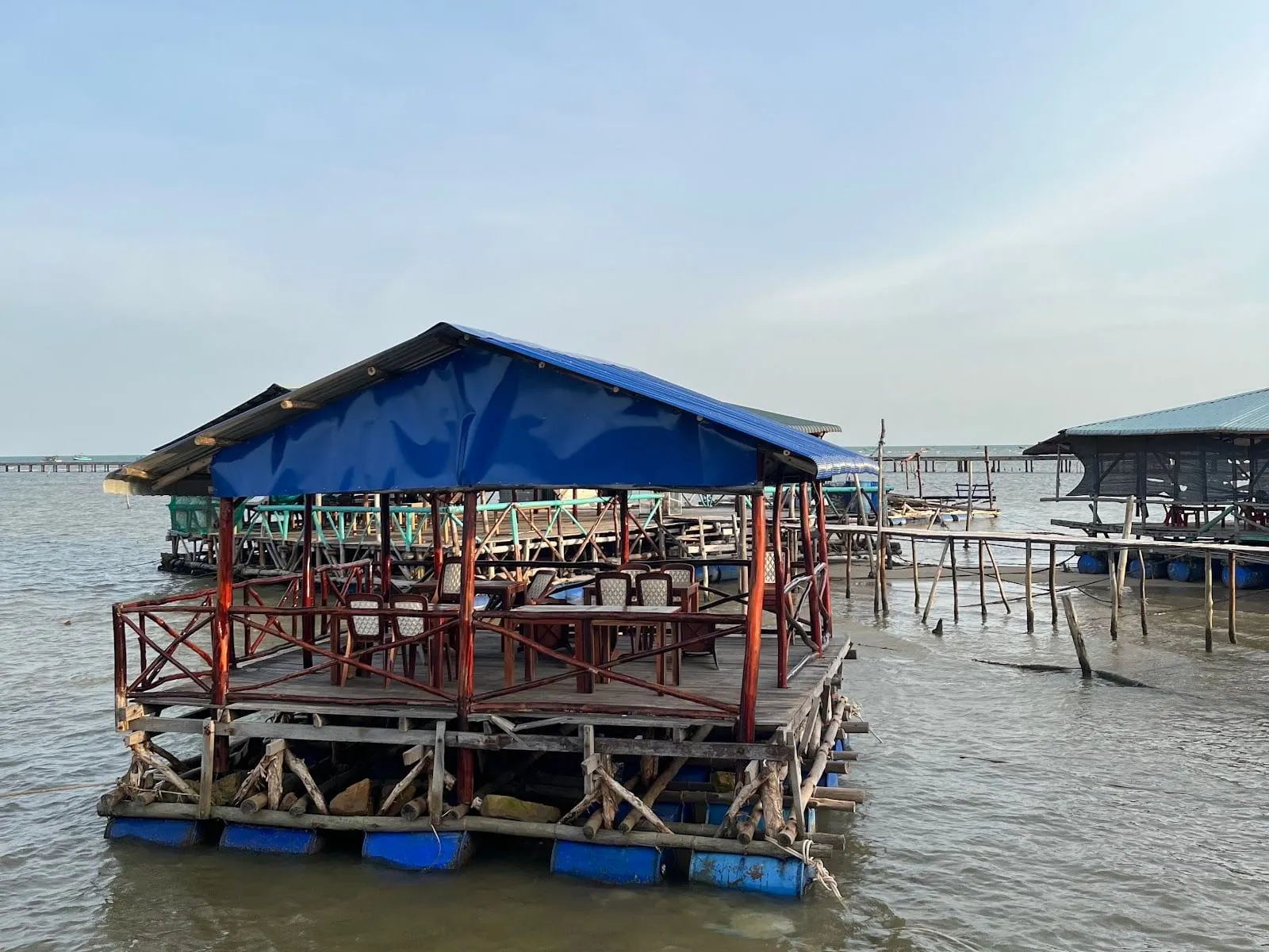 A stilt seafood restaurant with a blue roof over the shallow sea at Ham Ninh