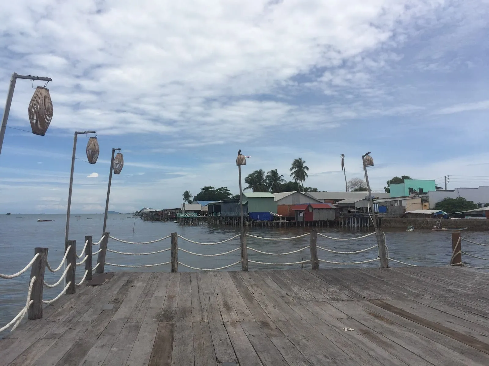 A wooden jetty with lanterns at Ham Ninh, with stilt houses over the sea