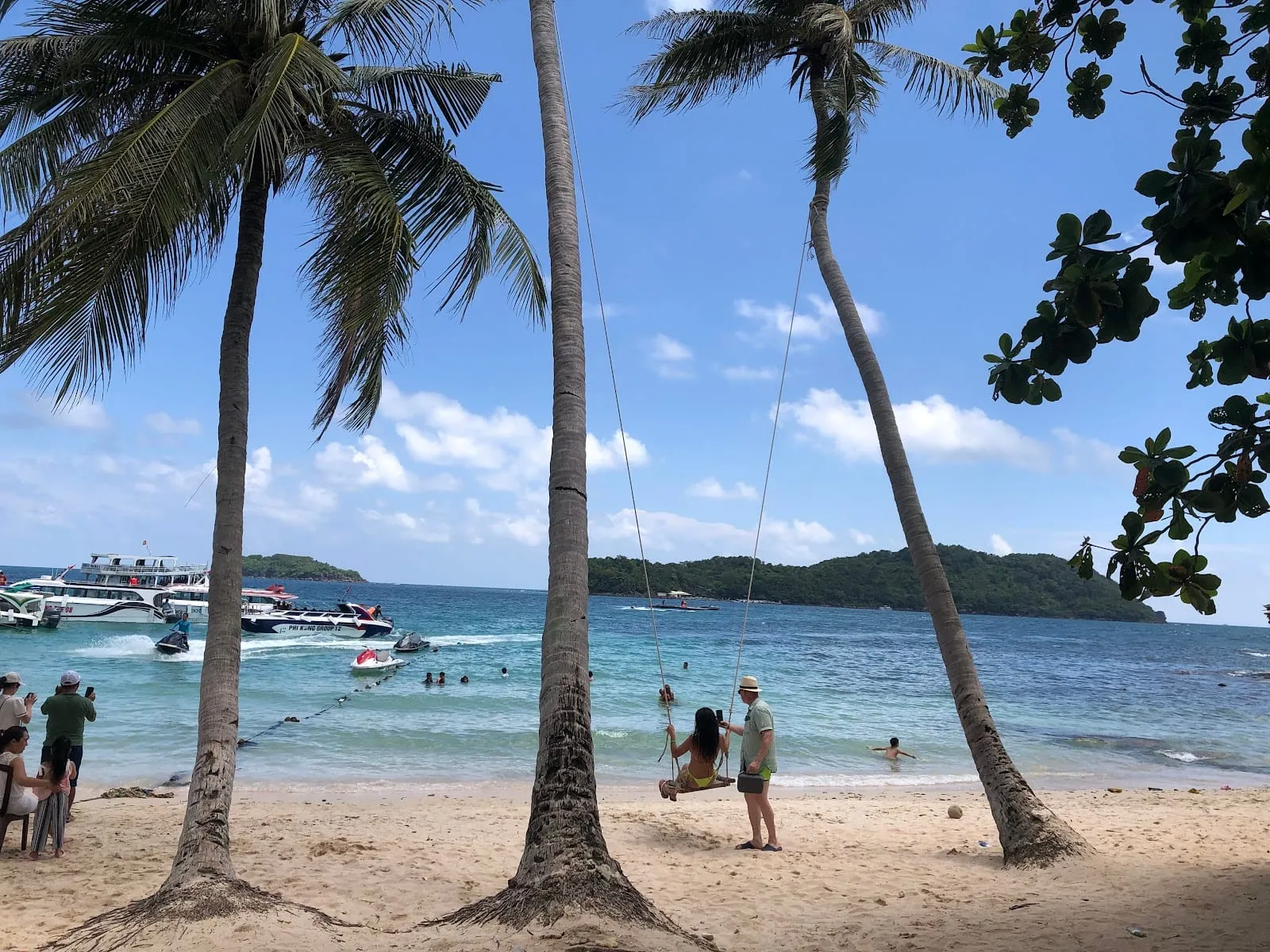 Palm trees, swings and tour boats on the white-sand beach at Hon May Rut