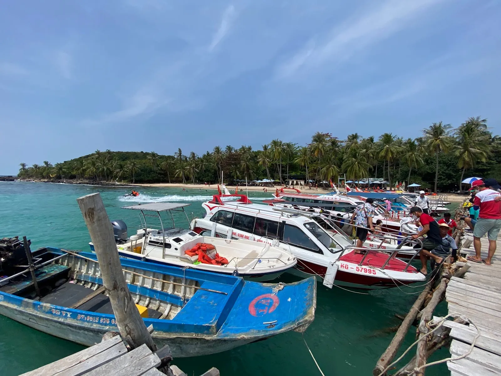Speedboats and wooden boats moored at the jetty at Hon Mong Tay, with palm trees behind