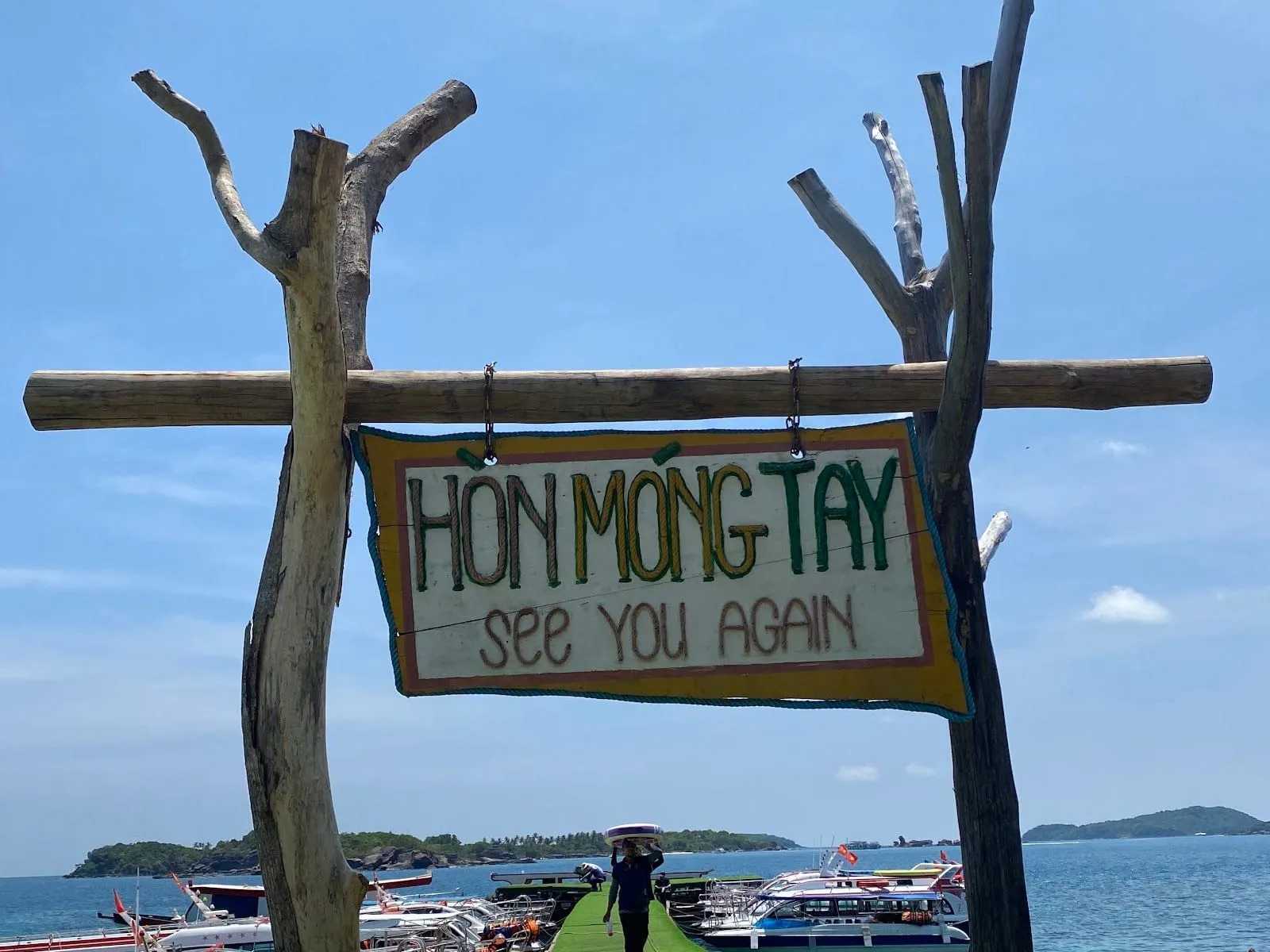 The Hon Mong Tay sign on the jetty, with boats and islands behind