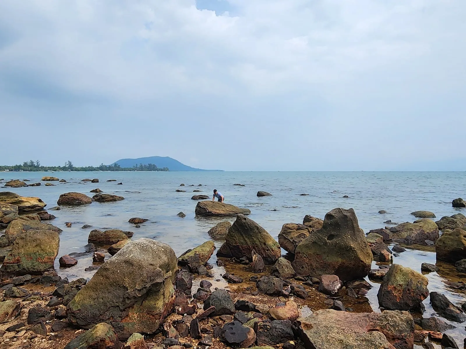 Rocks along the shore at Hon Mot, with the sea and distant hills