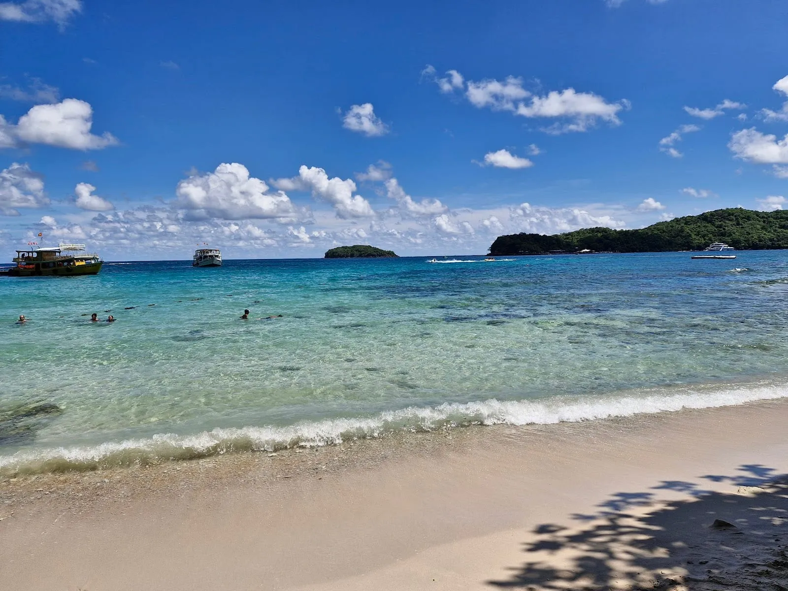 Clear shallow water and white sand at Hon Vong, with small islands on the horizon