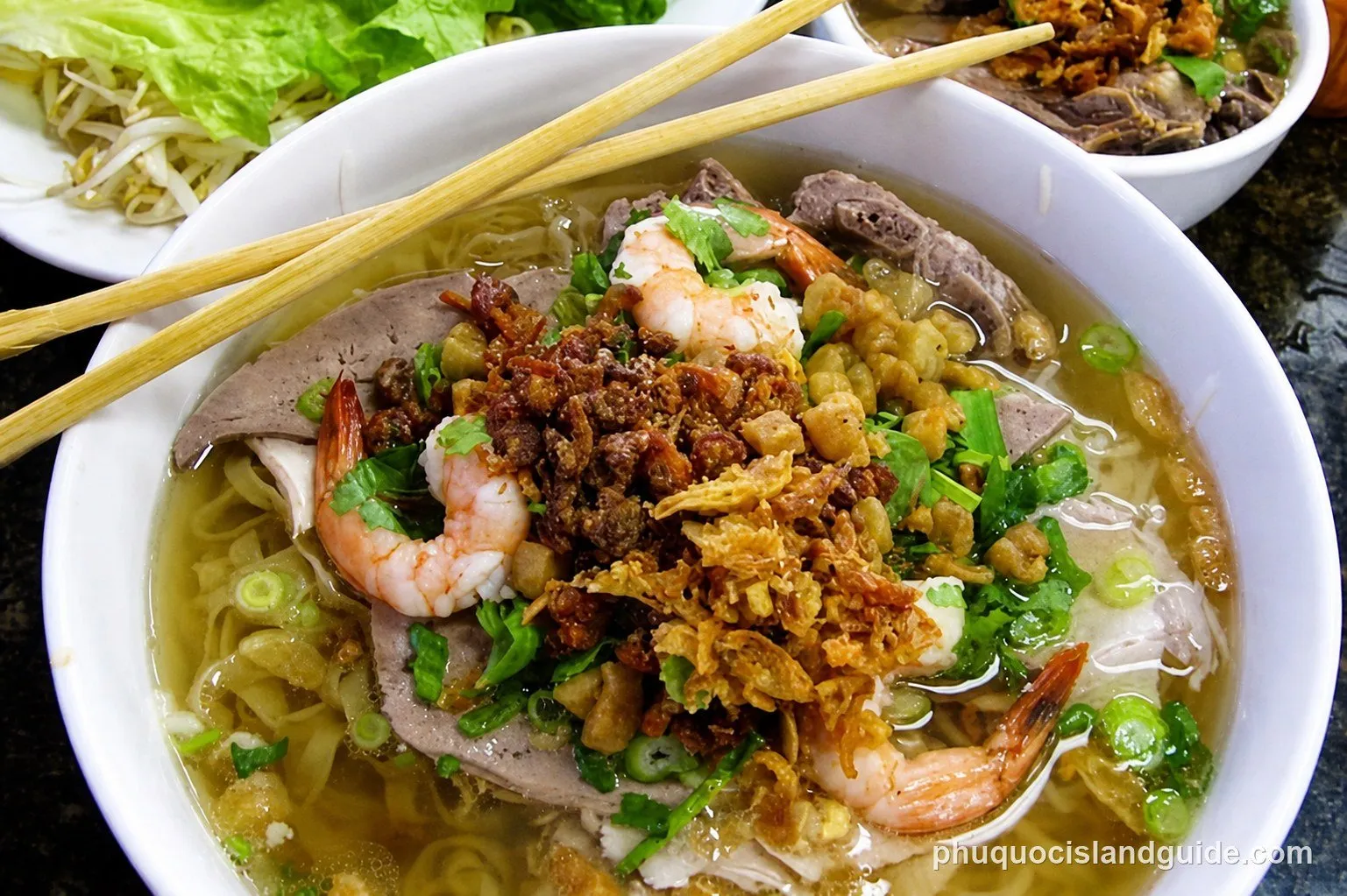 Bowl of hủ tiếu noodle soup with shrimp, meat and herbs