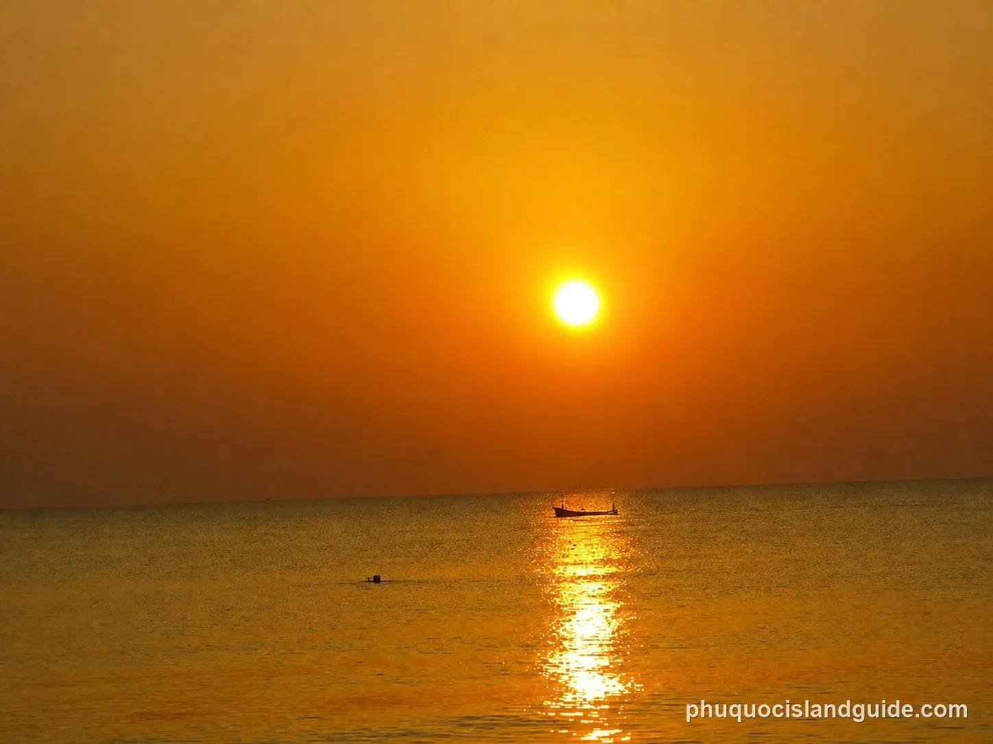 Orange sunset over a calm sea at Long Beach Village, with a small boat