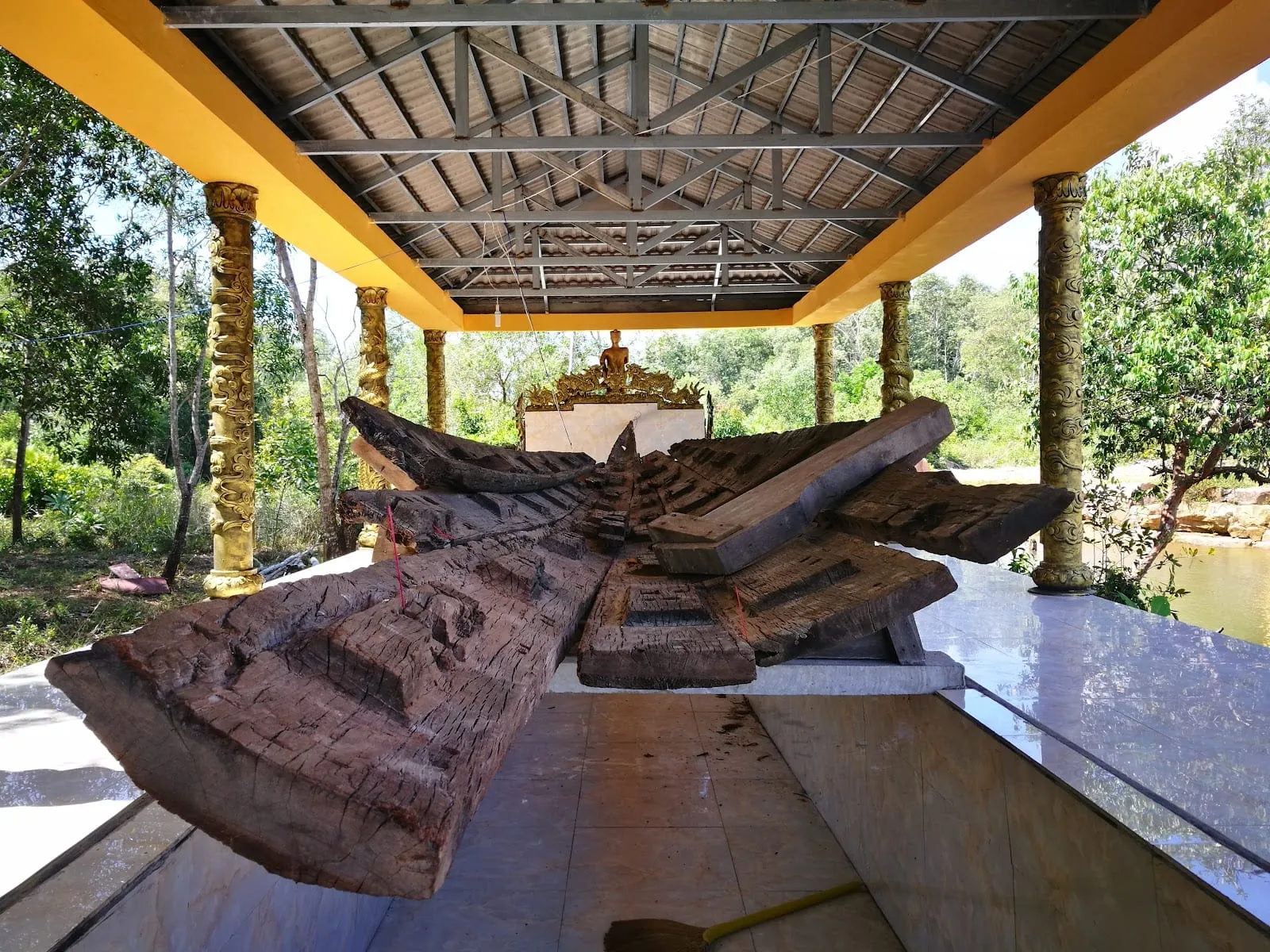 An old wooden boat on display under a roof in the shrine grounds at Cua Can
