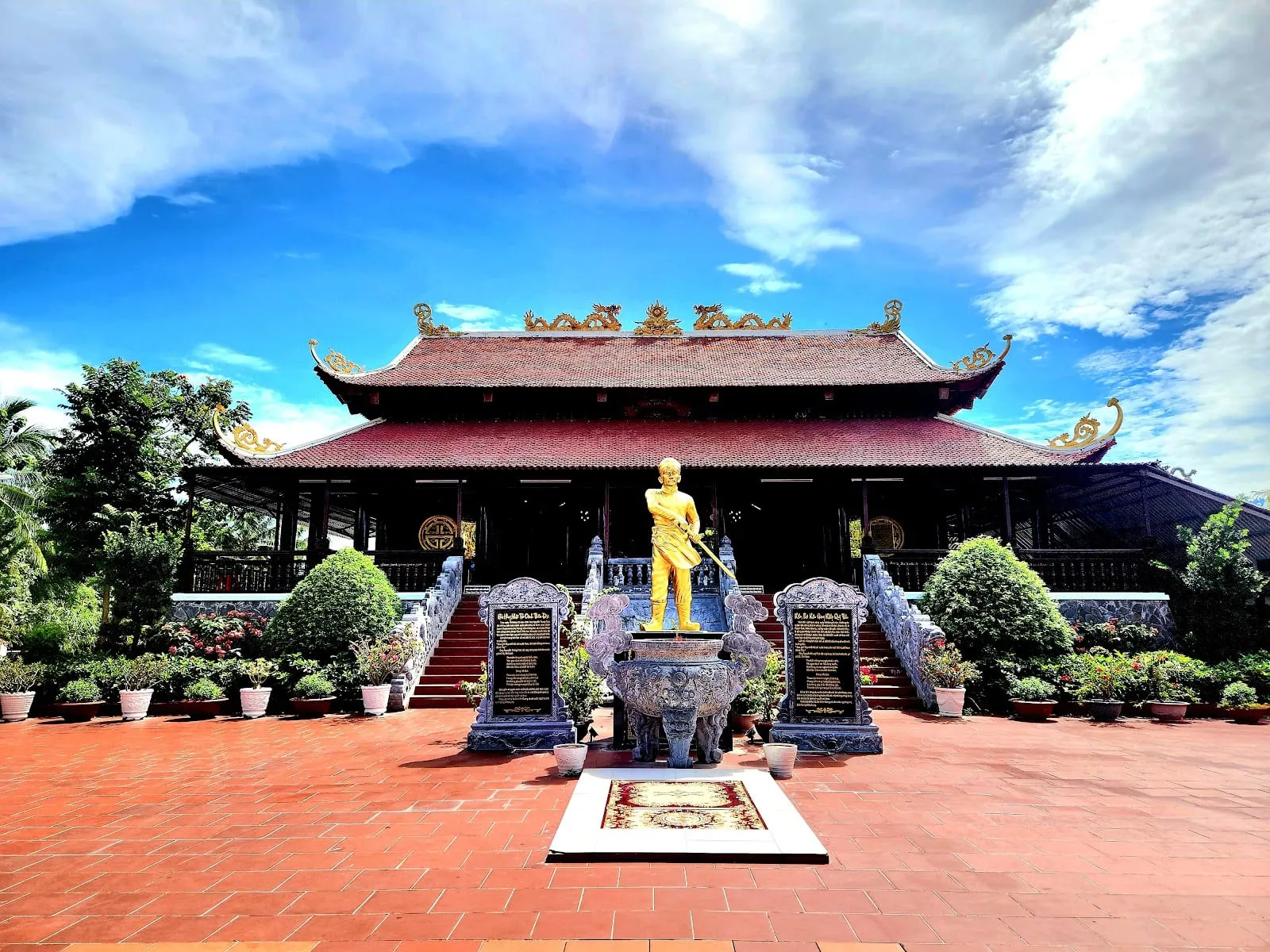 The main hall of the Nguyen Trung Truc temple at Ganh Dau, with a golden statue in the courtyard