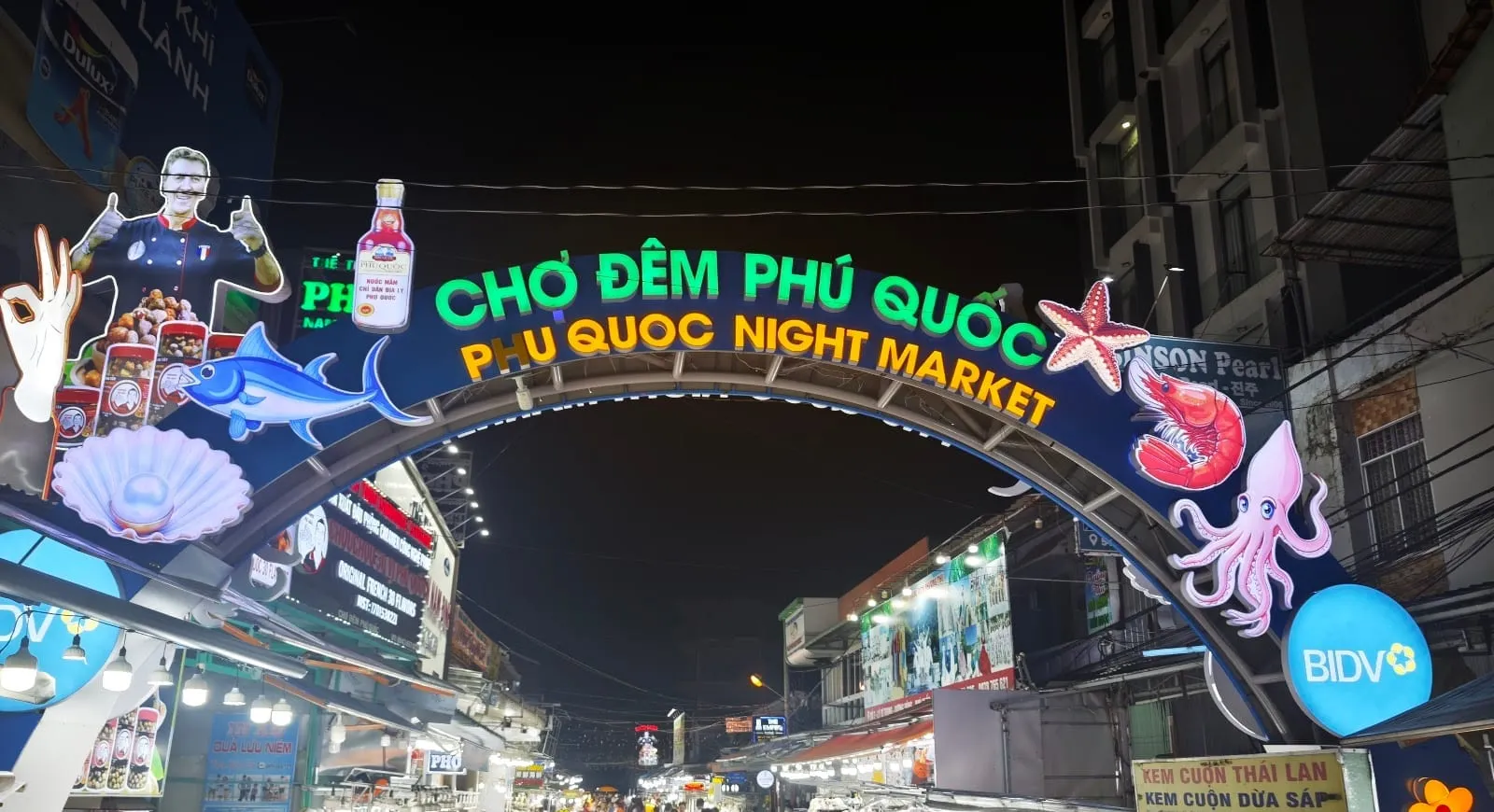 The illuminated gate of the Phu Quoc Night Market in Duong Dong, with stalls lining the street