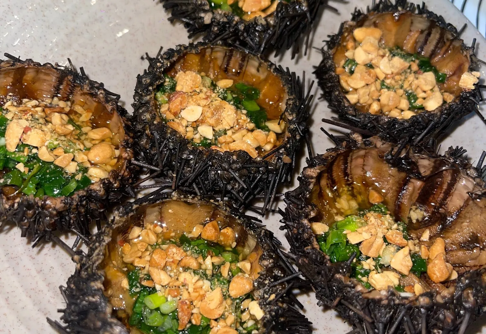Grilled sea urchins topped with spring onion oil and crushed peanuts