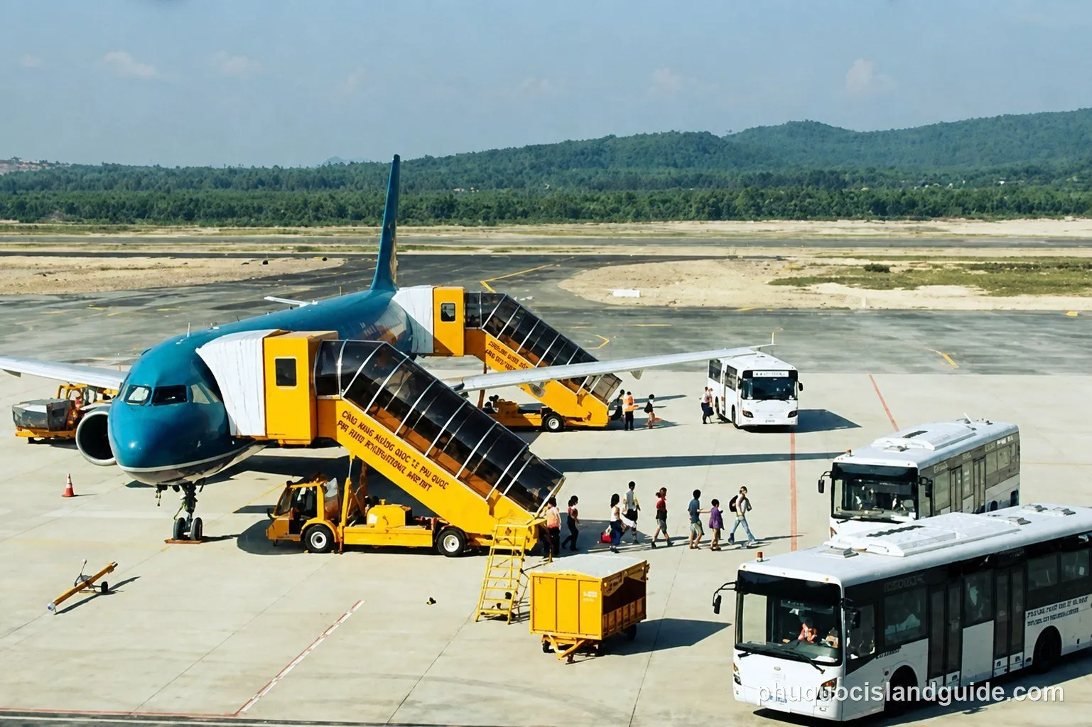 The apron and tarmac at Phu Quoc International Airport, with aircraft parked at remote stands and jungle-covered hills behind.