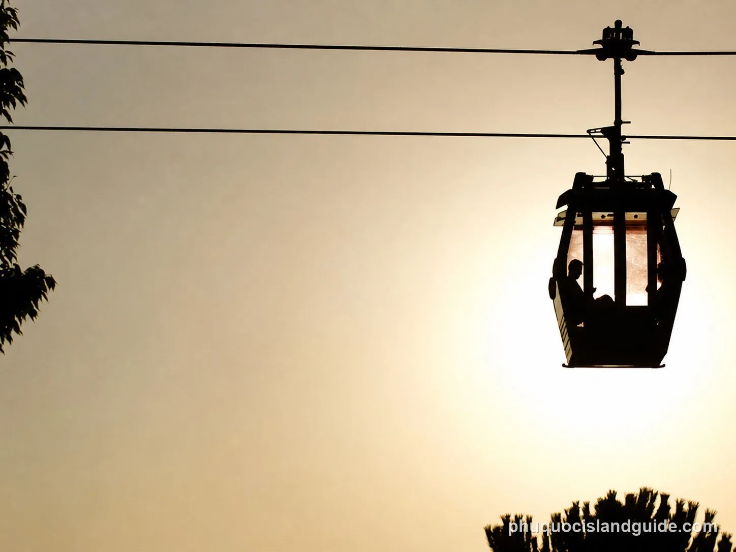 Cable car cabin with passengers silhouetted against a bright sky