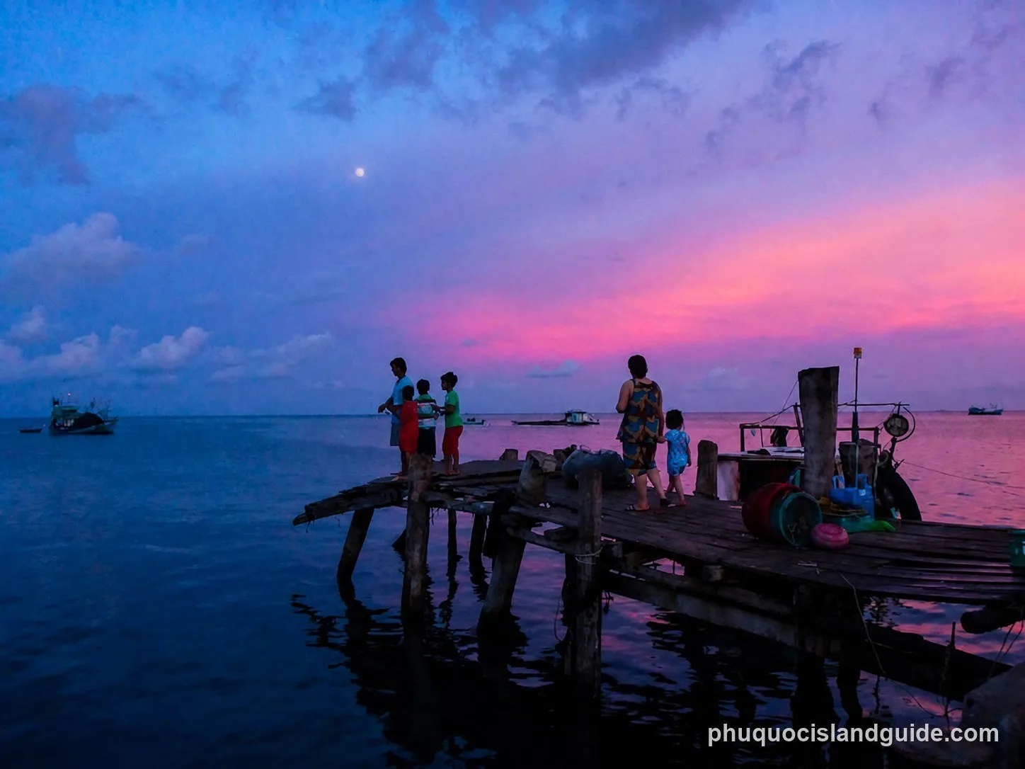 People silhouetted on a wooden pier at sunset at Ham Ninh