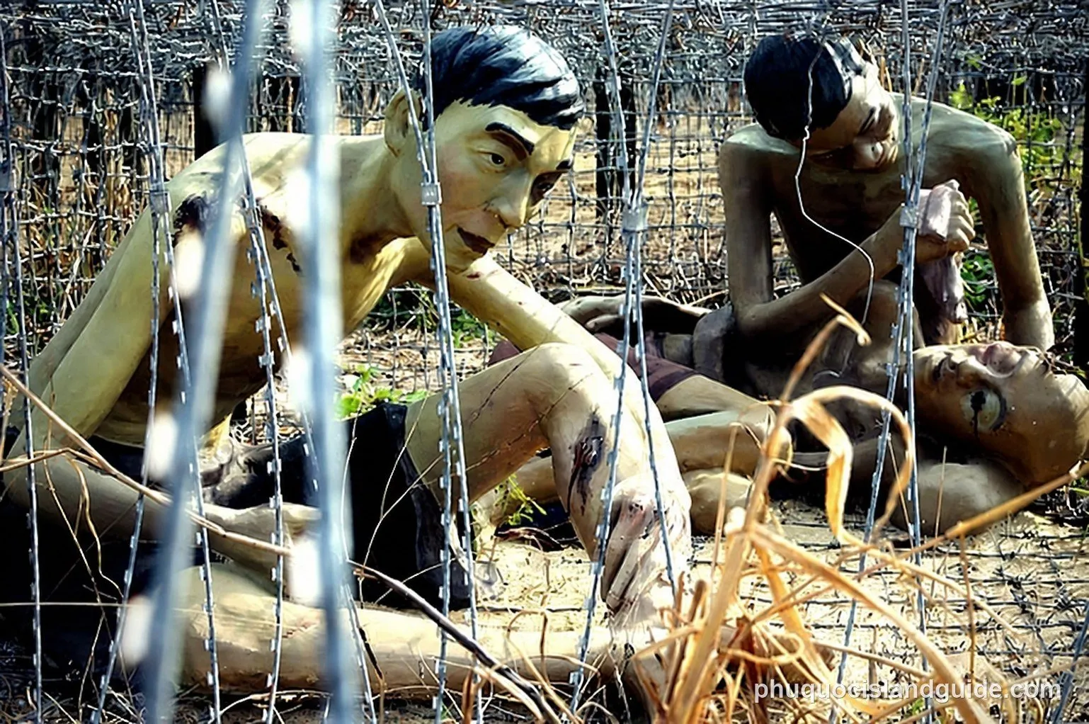 Statues of emaciated prisoners behind barbed wire at the Coconut Tree Prison