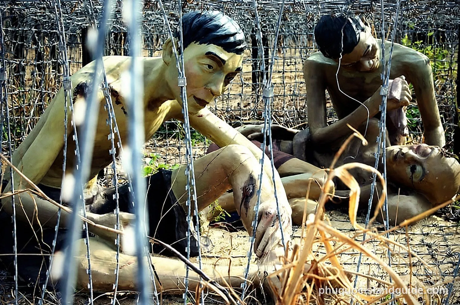 Statues of emaciated prisoners behind barbed wire at the Coconut Tree Prison