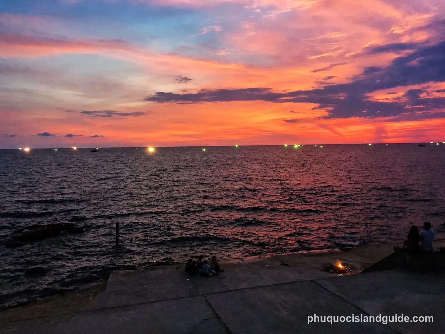 Sunset over the sea with the lights of squid-fishing boats on the horizon