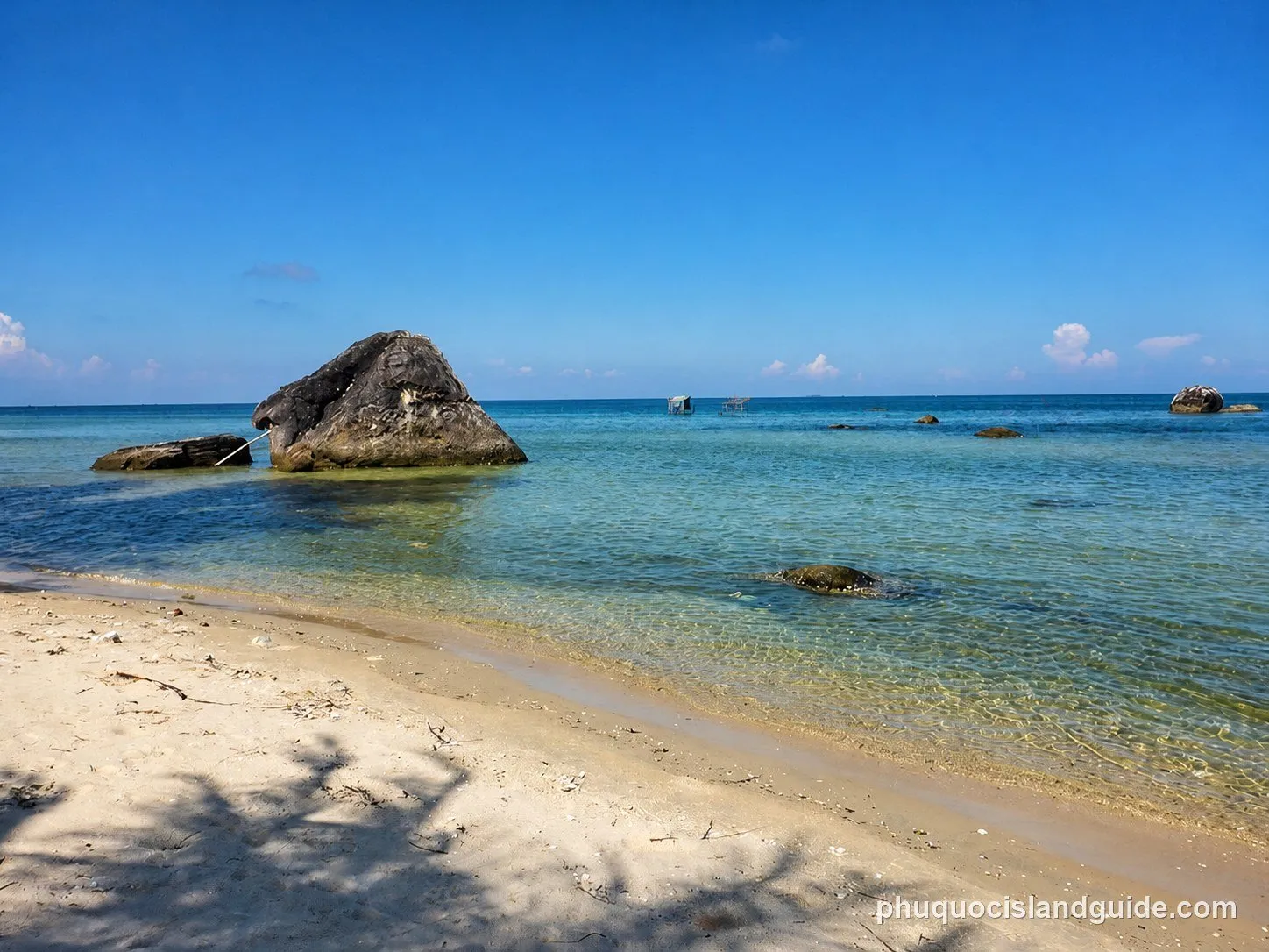 Large rocks in clear shallow water on a sandy beach