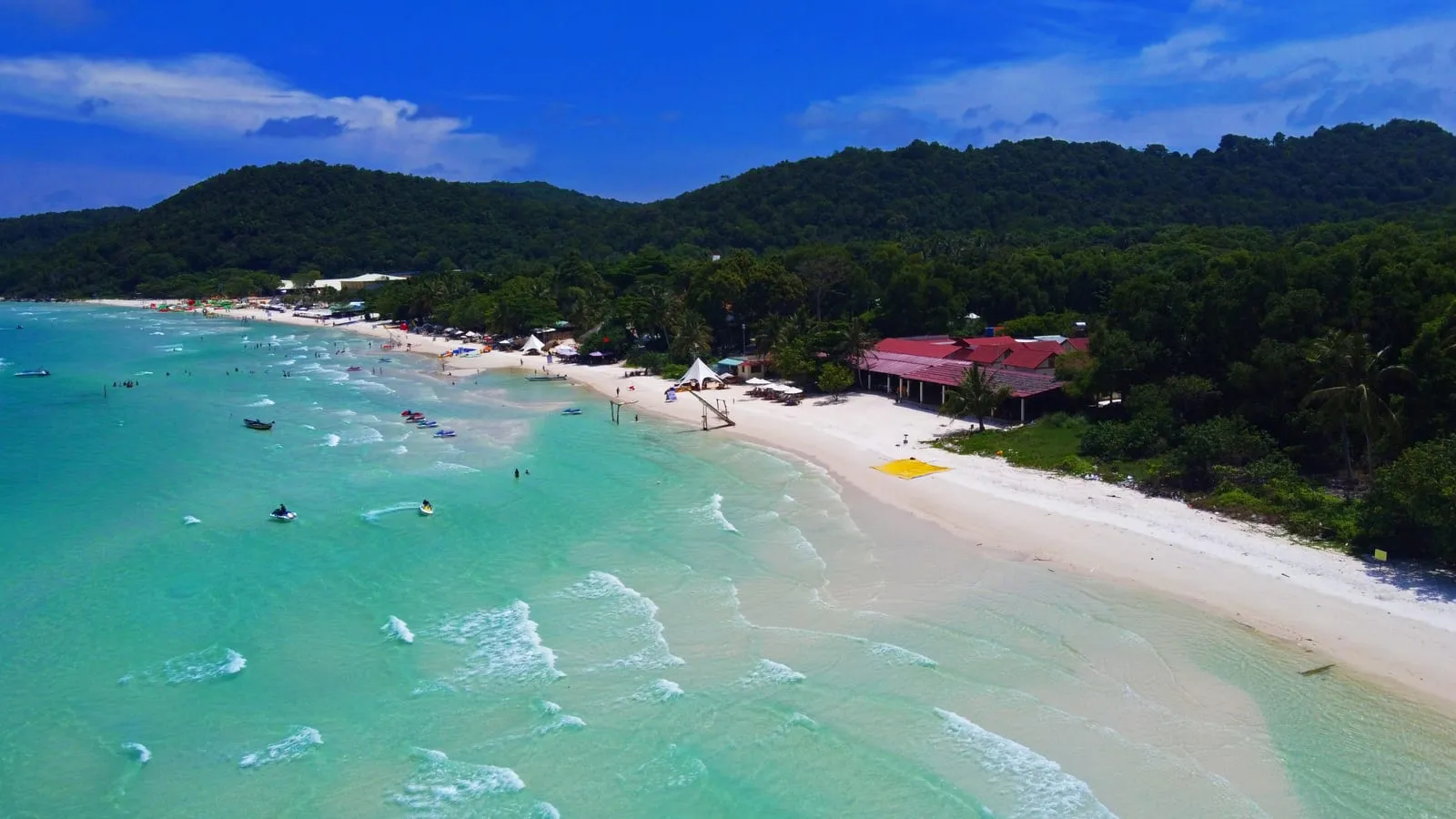 Aerial view of Sao Beach: white sand, turquoise water and a red-roofed beach restaurant