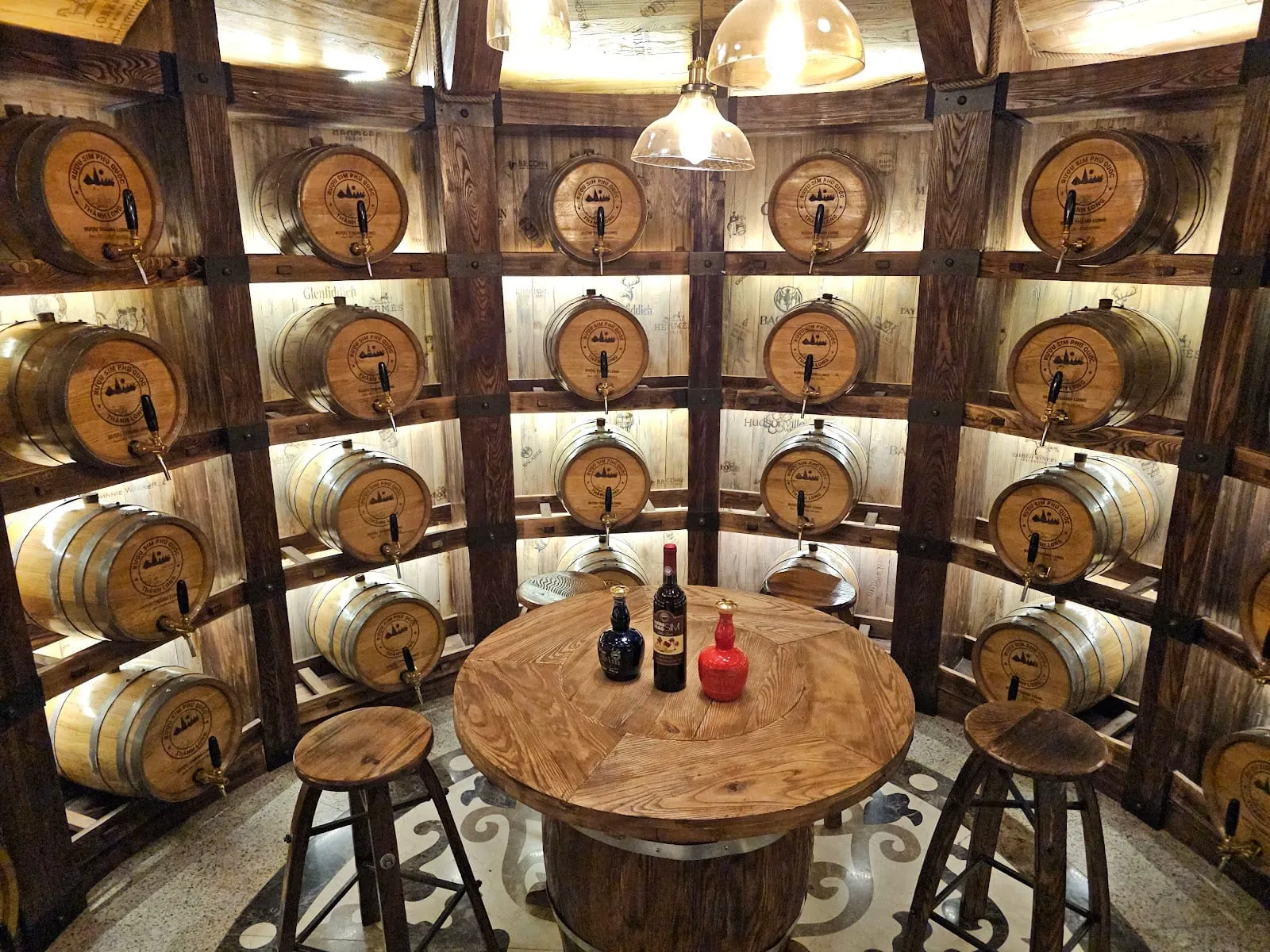 Wooden barrels and bottles of sim wine in the cellar at Vuon Sim Thanh Long
