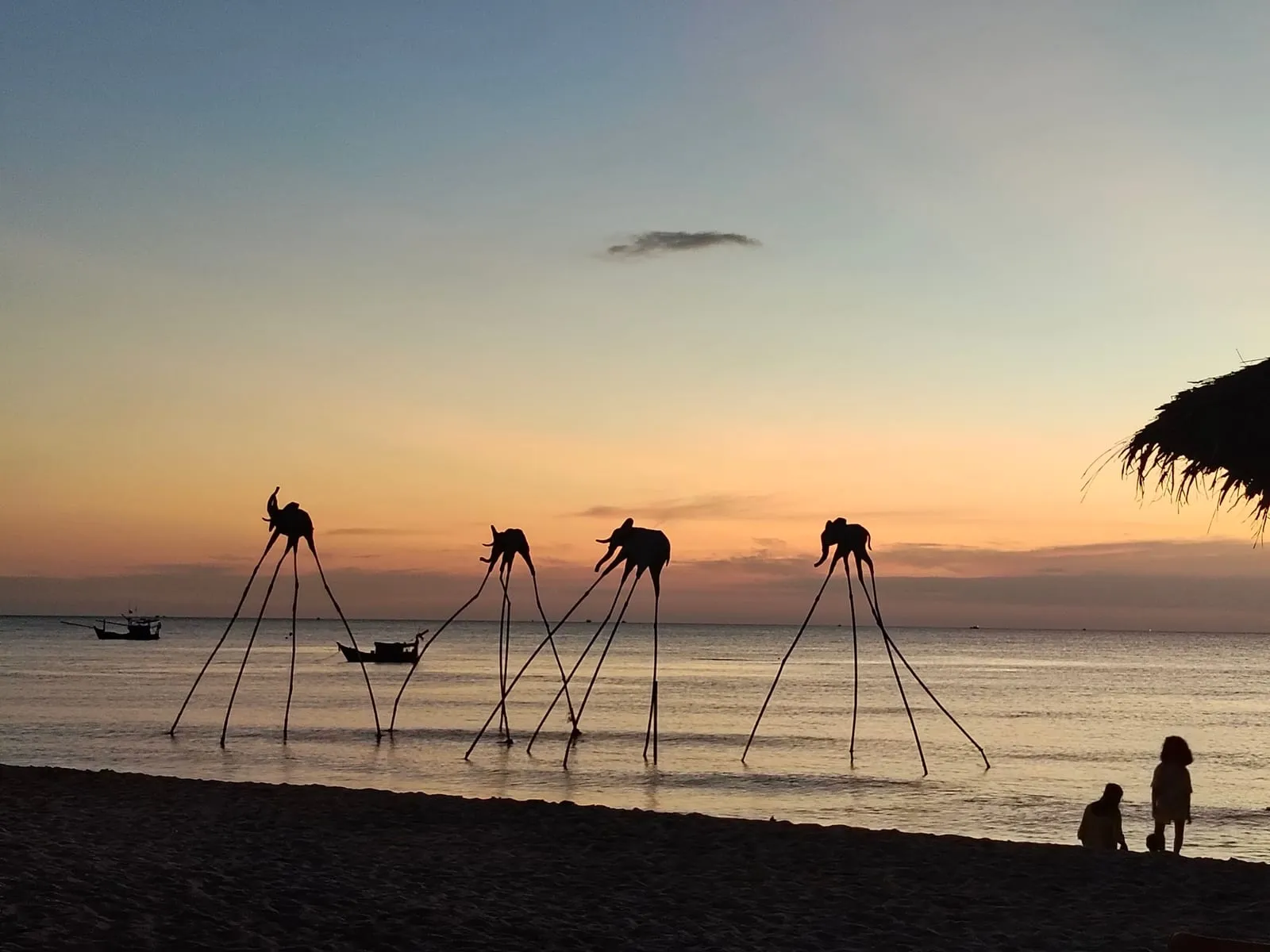 Sculptures standing in the sea at Sunset Sanato on Long Beach at sunset