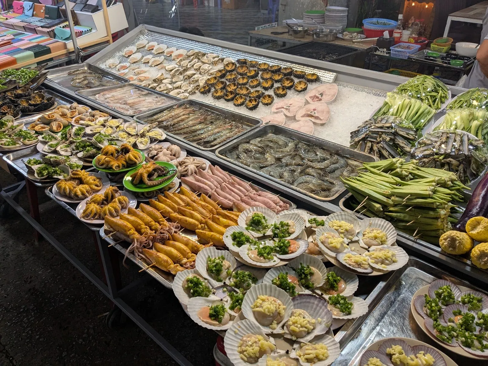 Scallops, squid, prawns, sea urchins and okra skewers laid out on ice at a seafood stall in the Phu Quoc night market